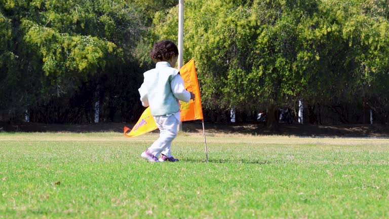 kid walking to hold the holy saffron flag with lord rama idol waving at ground at day