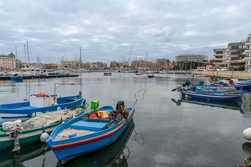 Syracuse, Italy - 28 December, 2023: colourful rowboats and fishing boats in the harbour between Syracuse and Ortygia Island