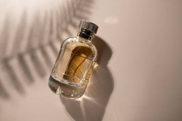 istock Golden perfume with leaf shadow on beige background, transparent spray bottle, sensual aroma, trendy fragrance 2150404655