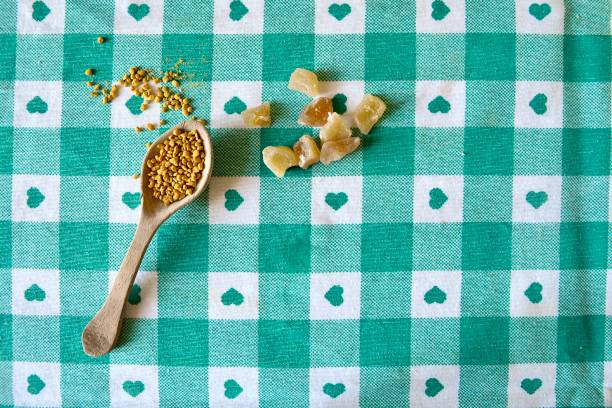 Healthy superfoods on a table with morning natural light, fresh pollen collected by bees in a handmade wooden spoon and dry ginger with copy space