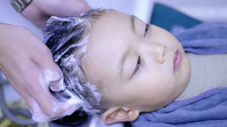 The hairdresser is washing the hair of a cute little boy