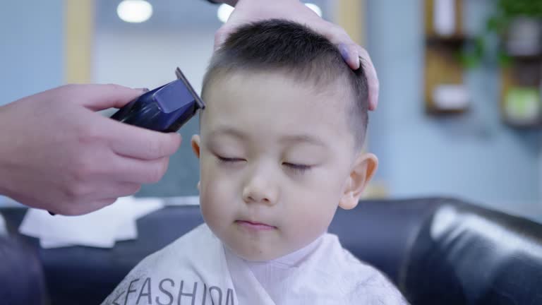 A cute little boy is getting a haircut