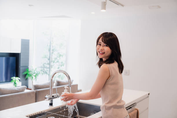 istock Young woman washing dishes in the kitchen 2150405935