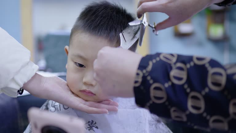 A cute little boy is getting a haircut