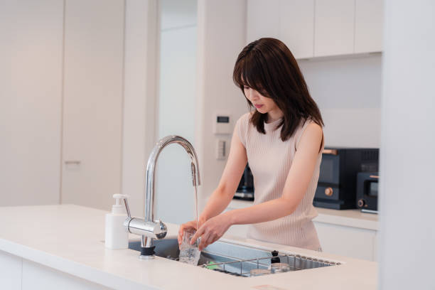 istock Young woman washing dishes in the kitchen 2150405940