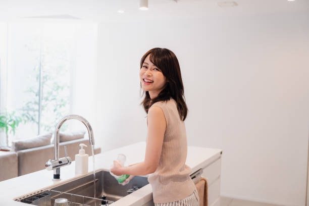 istock Young woman washing dishes in the kitchen 2150405942