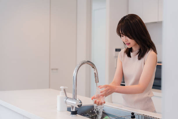 istock Young woman washing dishes in the kitchen 2150405946