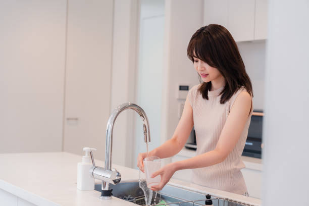 istock Young woman washing dishes in the kitchen 2150405947