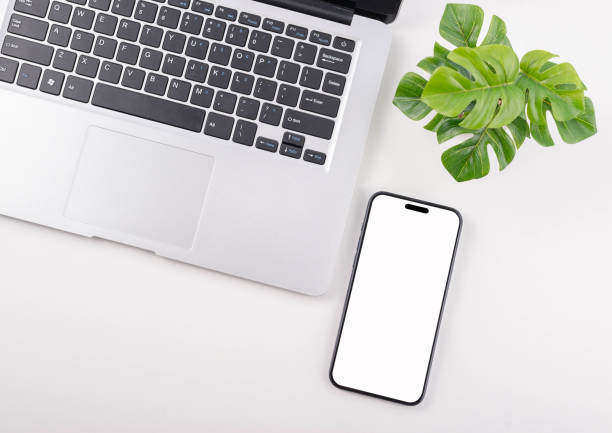 istock Modern white office desk table with laptop computer, smartphone with black screen over a notebook and cup of coffee. Top view with copy space. 2150409670