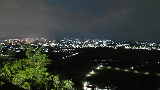 view of the land at night from the top of the hill. looks like lots of lights are on. You can see burning lights scattered across several points of land. so that the land looks like stars.
