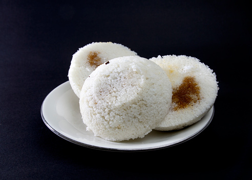 Steamed Rice Cake or Bhapa Pitha is a traditional dish of Bangladesh. Winter rice cake on Black Background. bite or broken pitha. Ingredients are rice powder, molasses, coconut, sugar etc.
