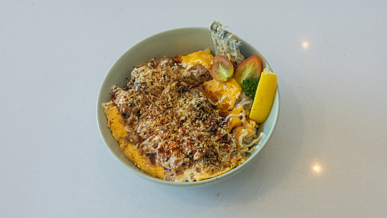 A bowl of food with a yellowish color and a white sauce
