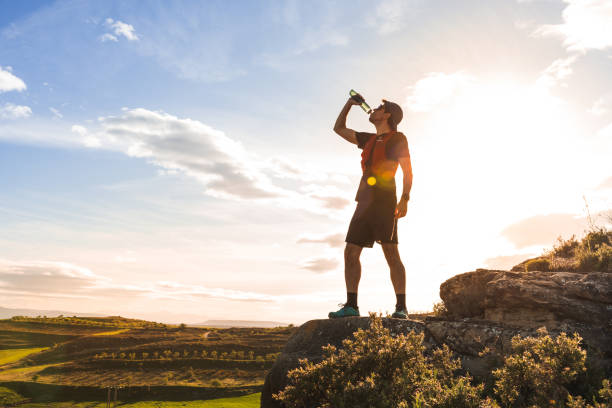 istock A trail runner drinking in a bottle against the backdrop of a Star shaped sun, 2150426065