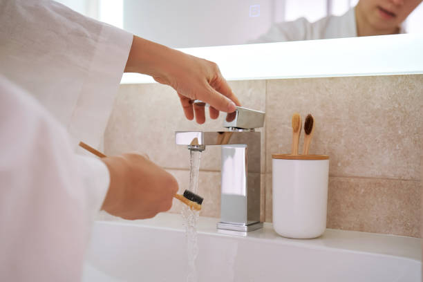 Women's hands under running water in the bathroom. Morning routine.