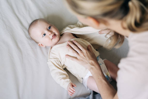 istock Mom dressing up baby after changing the diaper. 2150428532