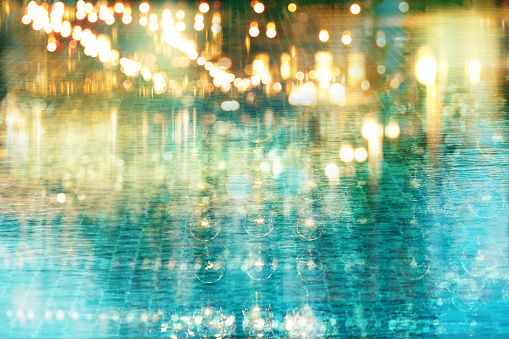 blur glowing  light of bar or pub reflection on blue water swimming pool summer party at night background