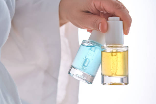 istock Two yellow and blue serums in a womans hands in a robe. 2150429342