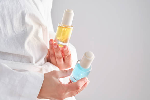 istock Two yellow and blue serums in a womans hands in a robe. 2150430106