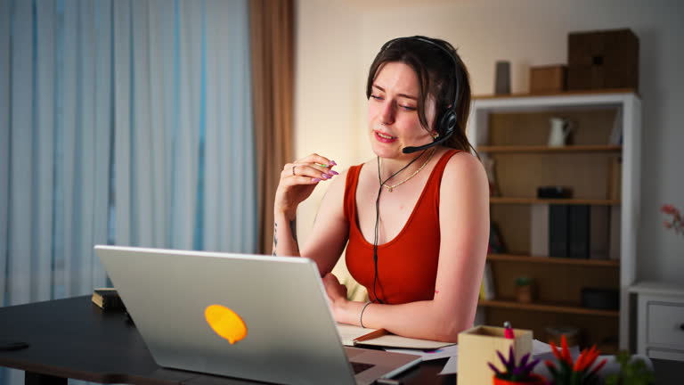 Young woman using a headset and laptop at home office