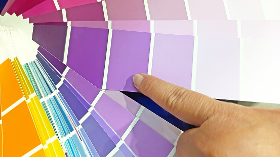 A Woman's Index Finger Points to a Catalog of Examples of Various Choices of Color Prints Color Palette Paint for Home Interior Design Renovations Photographed Close Up. High Quality Creative Designer