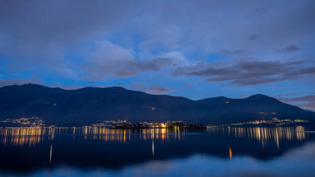 Calm waters of lake garda at sunset with the silhouette of the rocca scaligera castle and mountains in the background