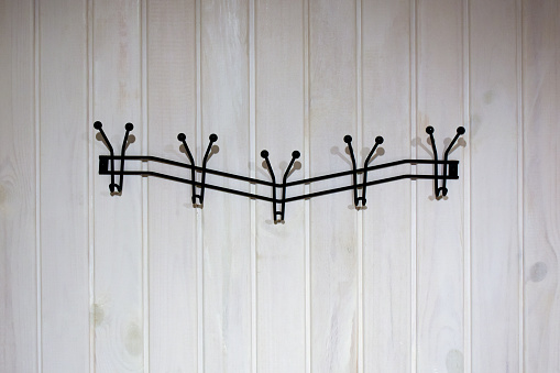 Clothing hook, empty metallic coat hanger on the white wood wall with copy space