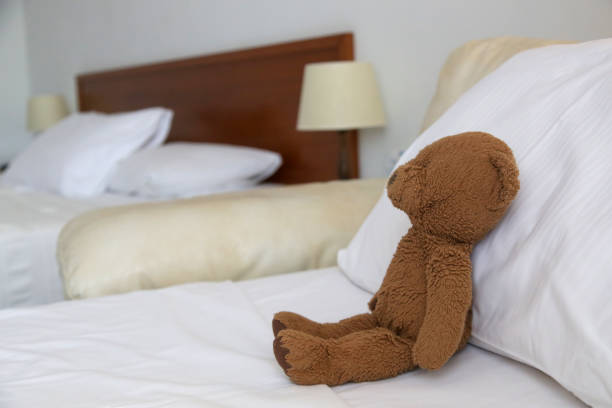 Cute brown teddy bear\nlaying on the bed