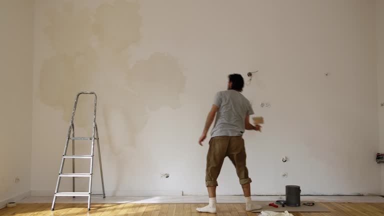 Scene Of A Man Limewash Painting A Wall Of A Renovated Room. Static Shot