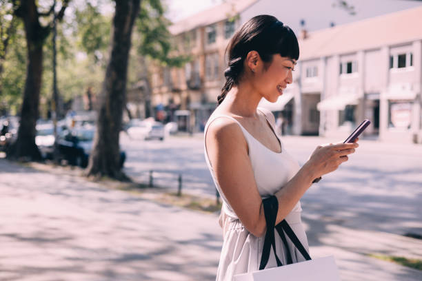 istock Elegant Woman Texting on Smartphone While Shopping Outdoors 2150451621