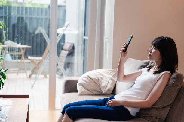 istock Young woman relaxing on sofa and using smartphone 2150455402