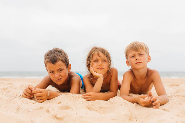 Group of children lying on a sand and get bored on their summer vacation