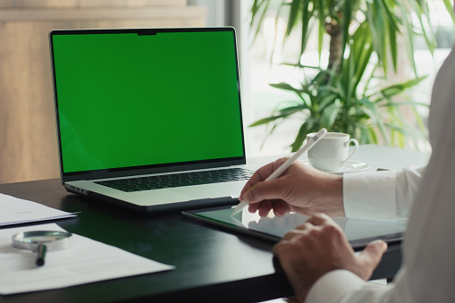 Businessman Using Laptop Computer With A Chroma Key Green Screen In The Office