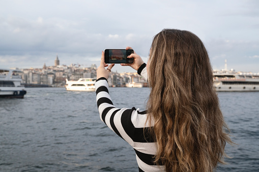 Young woman taking pictures by the sea in Istanbul, Turkiye