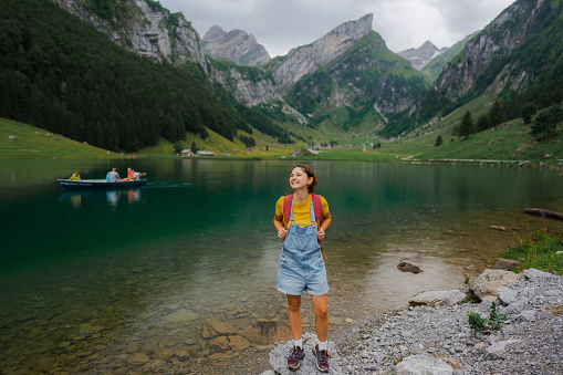Cheerful woman standing on the background of  Seealpsee lake in Appenzell