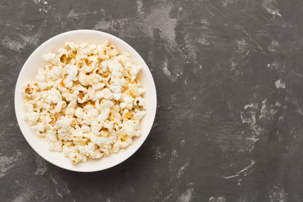 istock Tasty popcorn in bowl on concrete background, top view 2150462452