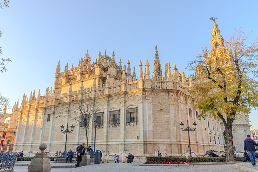 Seville, Spain - December 30, 2023:  A beautiful sunny late afternoon with the upper section of Seville Cathedral lighted up in golden color by the setting sun.  HDR encoded.