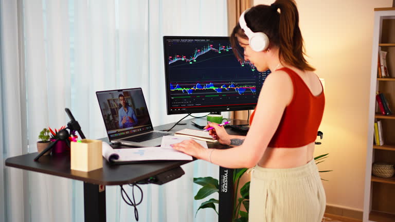 Young Business Woman working at an Ergonomic standing desk while walking on a treadmill, online meeting while checking Bitcoin or stock market price chart on a digital exchange,