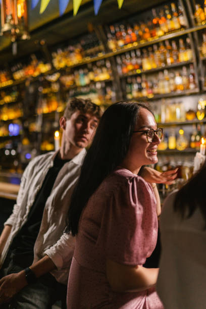 istock Lady and guy look to side with bar shelves in background 2150468667