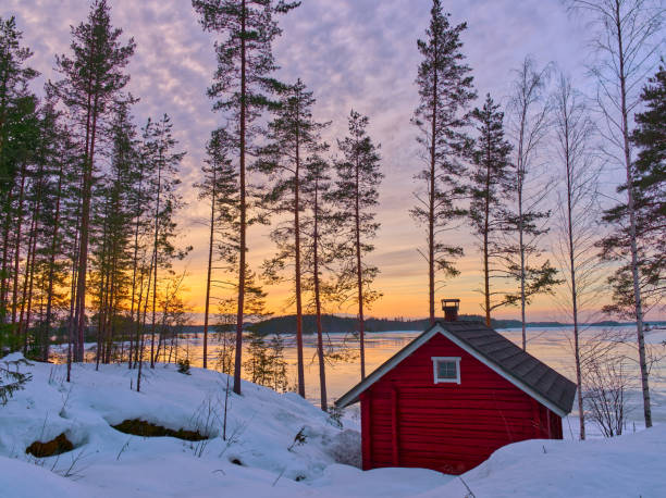 Red cabin in the woods close to lakeshore in sunset colors, Finland