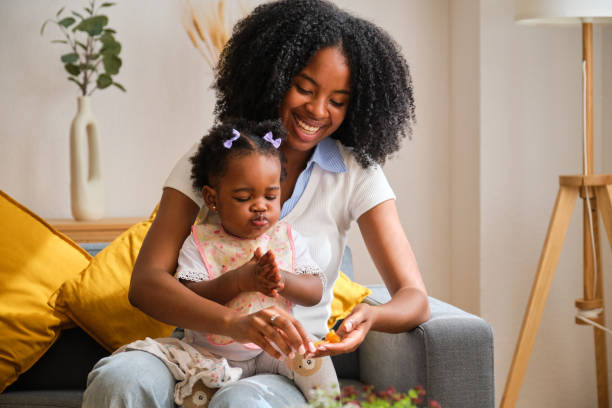 istock A toddler clapping and mother feeding a tangerine. 2150471950