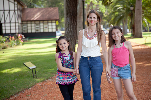 Happy mother and daughters having fun outdoors - Public park in Buenos Aires city