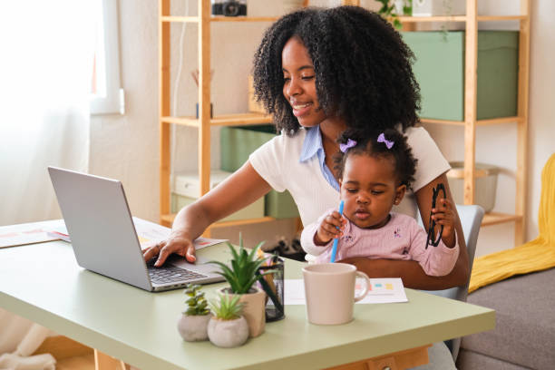 istock A woman is working on her laptop while holding her baby. 2150472626