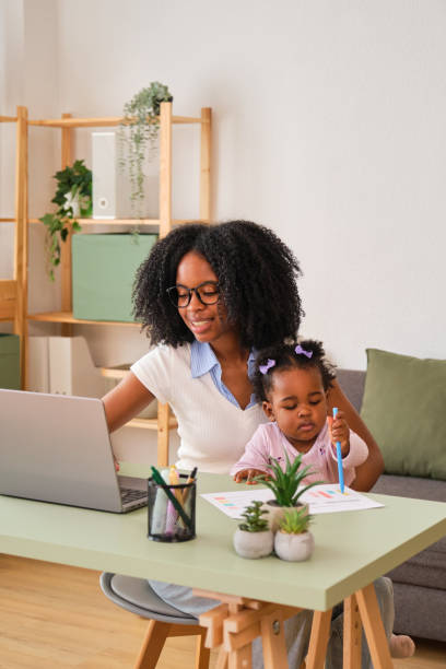 istock A woman is working on her laptop while holding her baby. 2150472636
