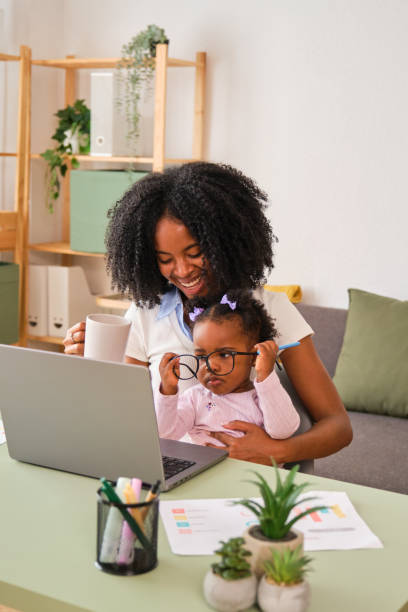 istock A woman is working on her laptop while holding her baby. 2150472658