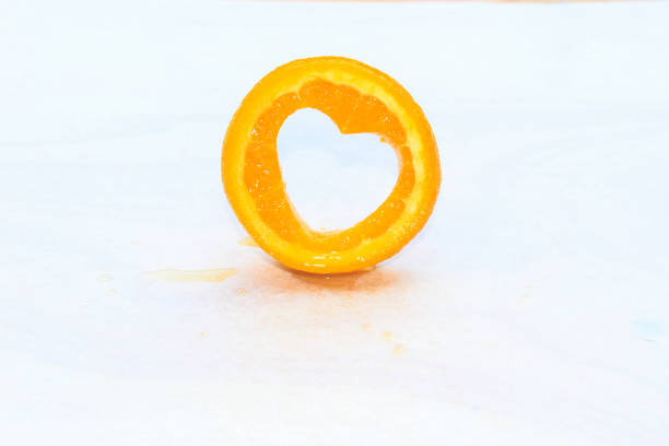 A delicious orange slices with a love shape hole on the orange on white background.