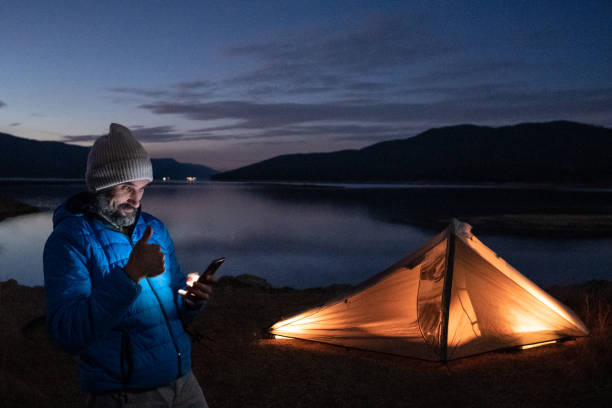 istock Thumbs up. Man has online meeting while night camping at lake. 2150480403