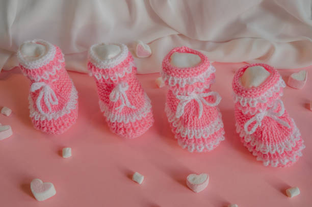 istock Pink knitted booties on pink background with marshmallow hearts 2150480520