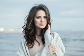 Nice brunette lady outdoor portrait. Healthy woman against blue sea and sky cloud background