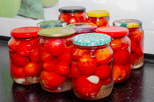 Glass jars with red tomatoes filled with brine. Preparations for the winter, canning tomatoes.