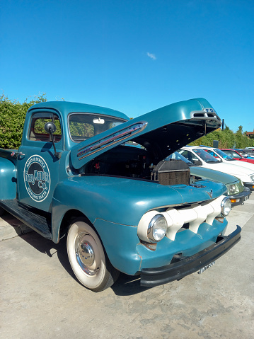 Avellaneda, Argentina - May 7, 2023: Old blue 1950s Ford F 1 V8 pickup truck open hood in the street at a classic car show. Copy space